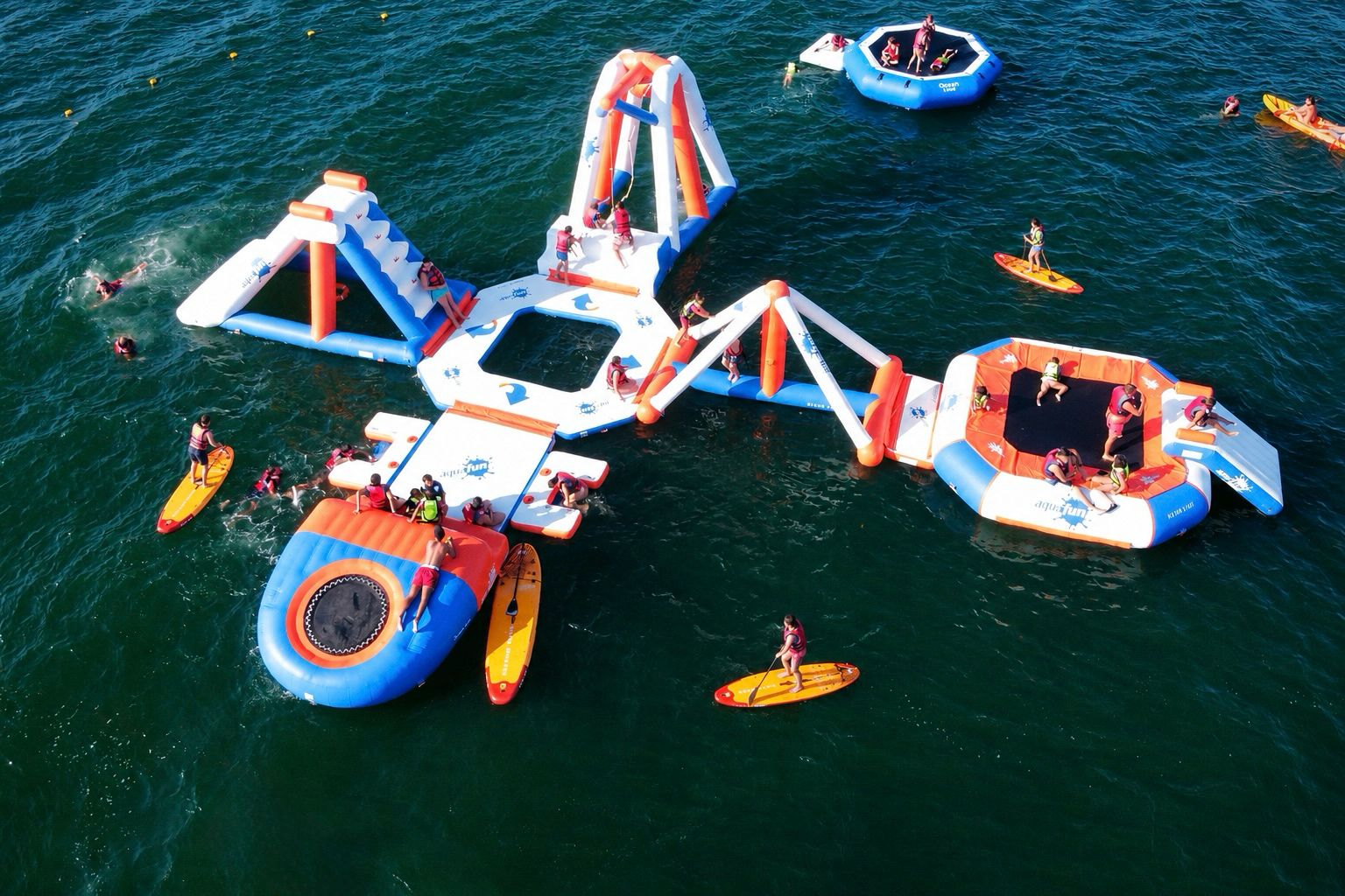 Vista aérea de Ozean Park con parque acuático flotante, paddle surf y usuarios en el mar